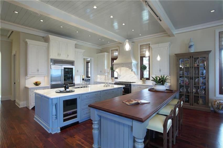 Cottage style kitchen with two light blue painted islands with carrara marble and wood countertop