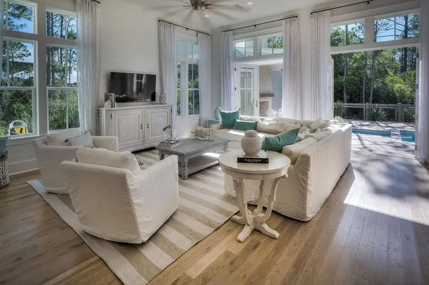Cottage style living room with white furniture french doors and window views to backyard