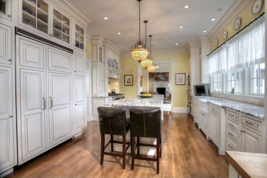 Country kitchen with white cabinets and hidden freezer fridge with breakfast bar island and white granite counters