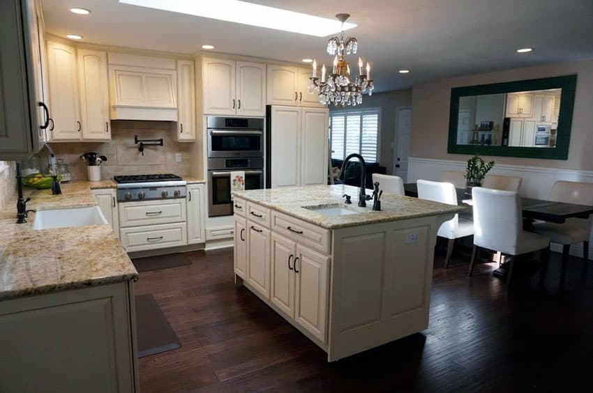 Kitchen with dark flooring, cabinets with black metal handle and antique candelabra style chandelier