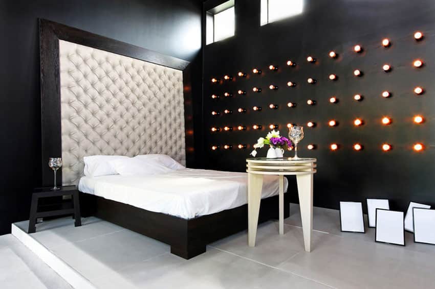 Custom designed black bedroom with rows of wall lights and tufted headboard