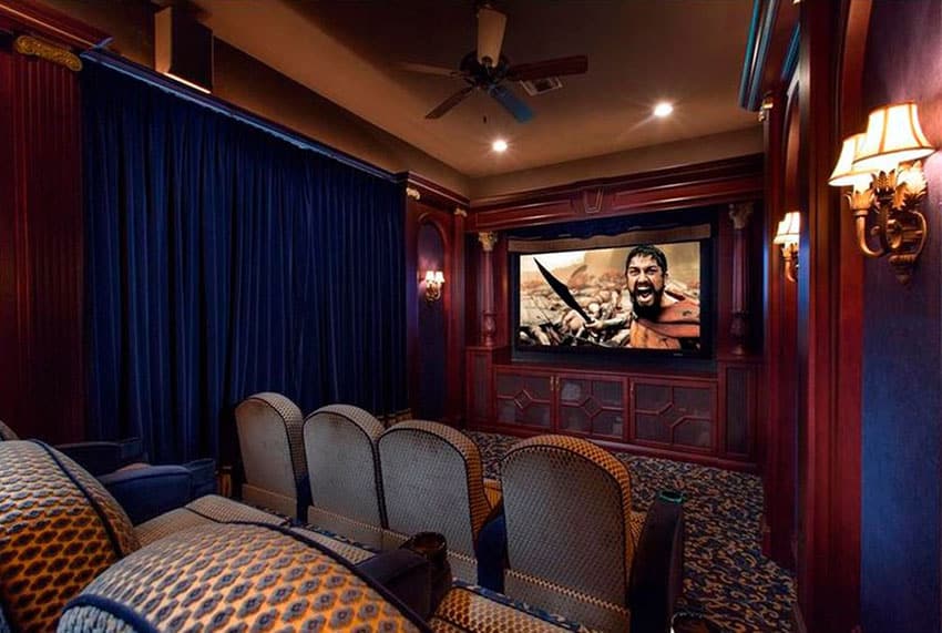 Custom home movie room with decorative wood theater seats and wall sconce lighting