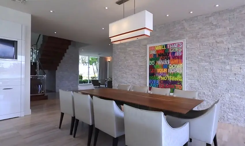 Dining room in modern house with stacked stone accent wall next to kitchen