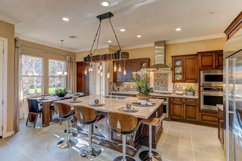 Eclectic kitchen with marble slab island chrome bar stools and ceramic flooring