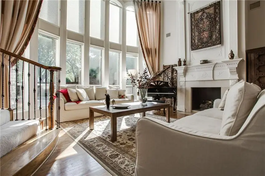 Elegant traditional living room with fireplace, baby grand piano and cream color furniture