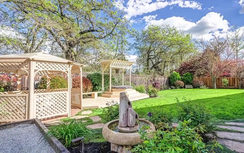 Gazebo and pergola in backyard with stepping stone path and water fountain