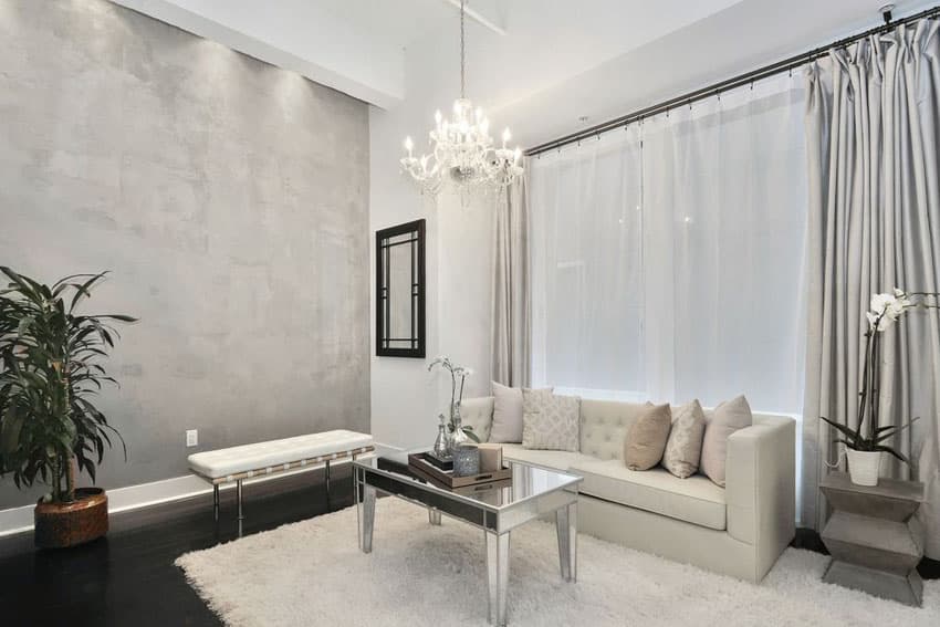 Gray and white living room with shag area rug, curtains, sofa and chandelier