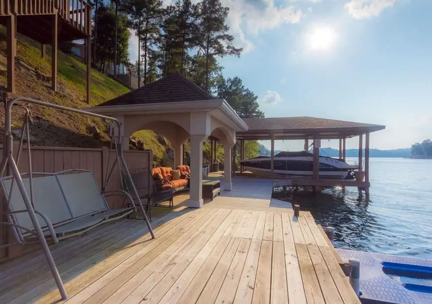 Lake side deck with wood gazebo and sitting area next to boat house
