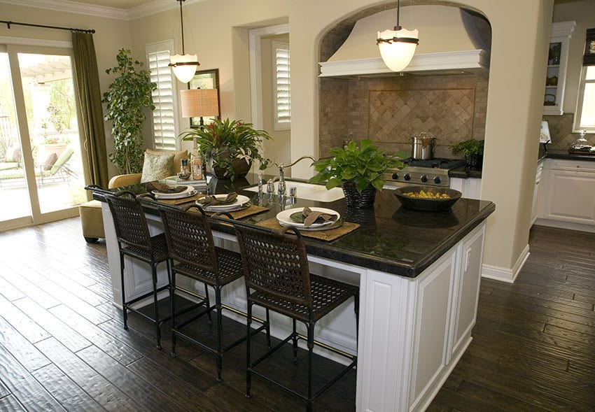 Large kitchen island with white cabinet dark counter and seating