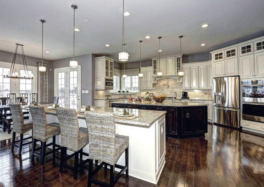 Dark cabinet and white painted islands and cream color raised panel cabinets