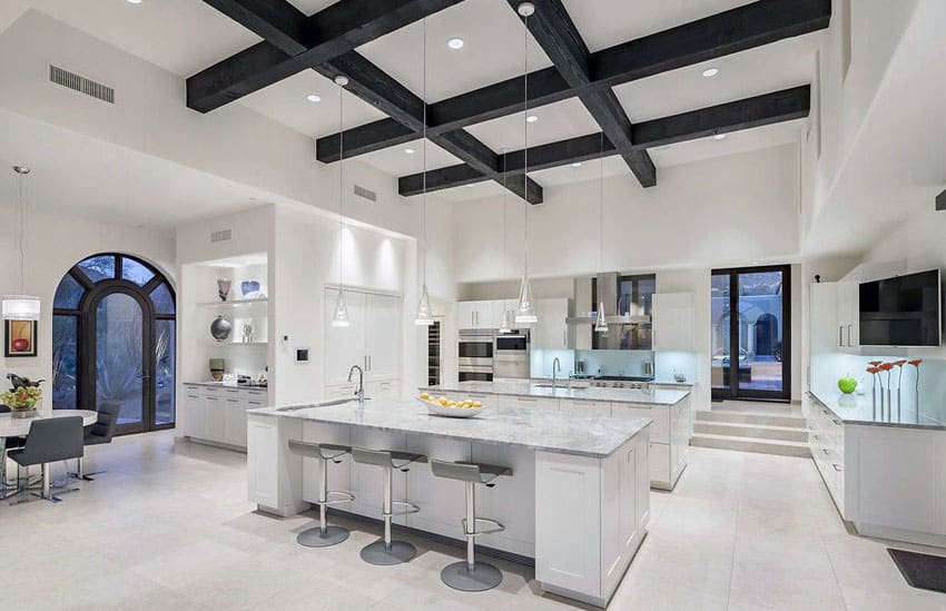 Luxury contemporary kitchen with two islands, carrara marble counters and wood beam ceiling