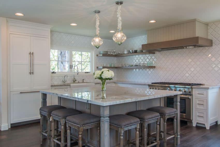 Luxury kitchen with large breakfast bar island topped with carrara white marble counter and pendant lights