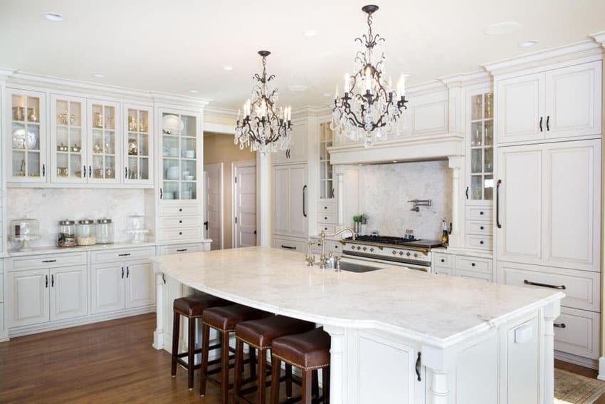 Luxury kitchen with white glass face cabinets carrara marble counter island and two chandeliers