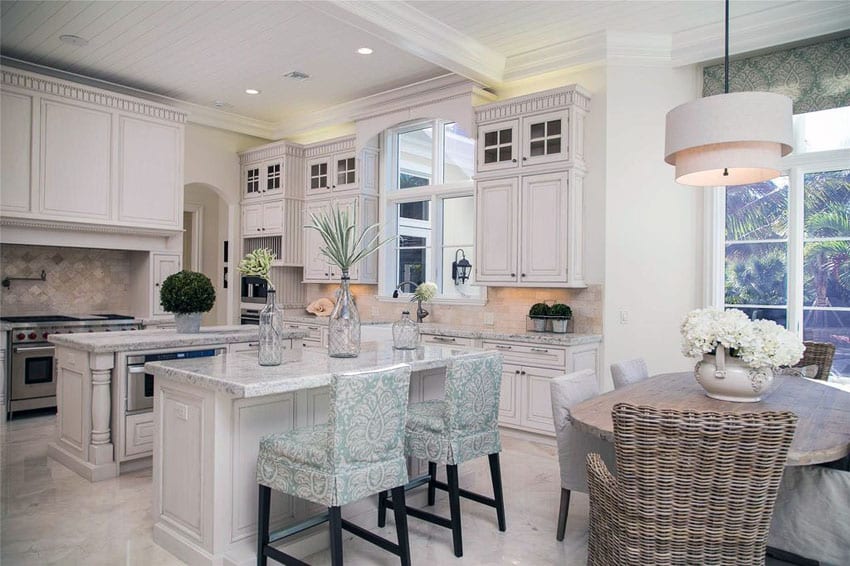 Luxury traditional kitchen with two islands, damasco white marble counters and white cabinetry with glass doors