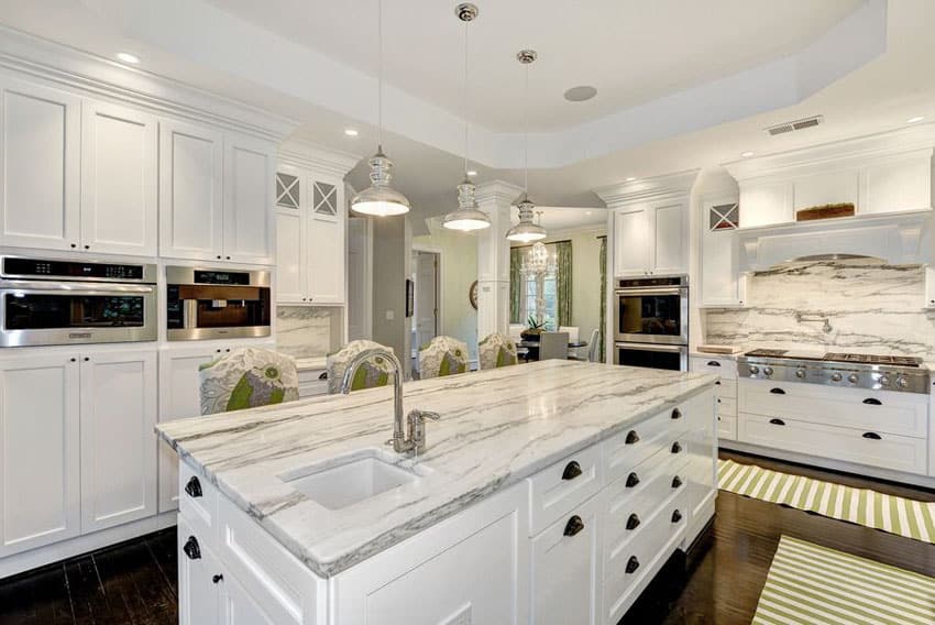 Transitional style kitchen with classic white cabinets, oak hardwood flooring and contemporary calacatta marble countertops and pendant lights