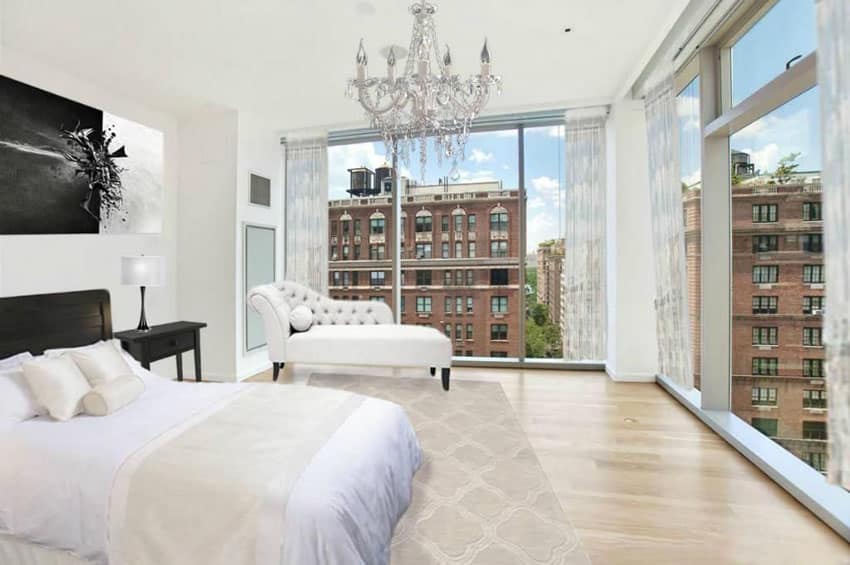 Bedroom with wrap around window view and white tufted lounge chair