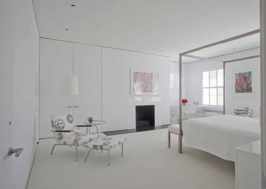 Bedroom with high glass white built-in storage walls and metal bed