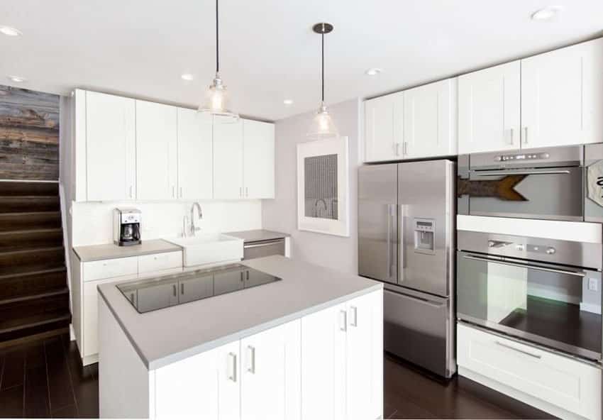 Modern kitchen with white cabinets, dark wood floors and corian solid surface counters