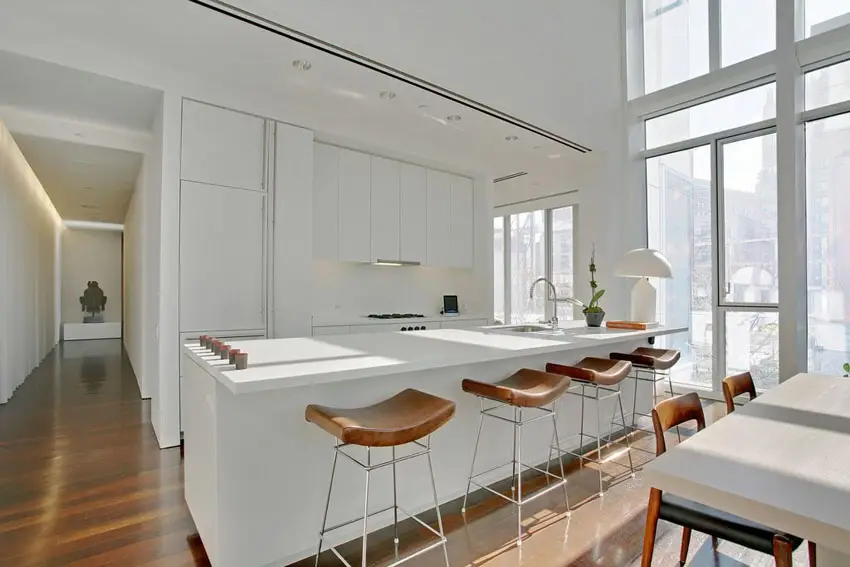 Modern white kitchen with quartz counters, flat panel cabinets and open dining area