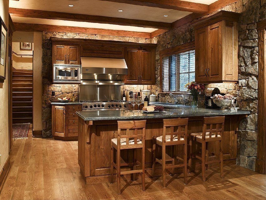 Kitchen with grey counters, wood bar chairs and stacked stone wall