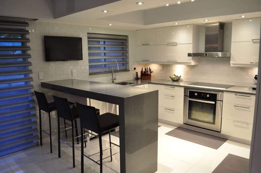 Small modern kitchen with gray quartz counter peninsula and white gloos cabinets