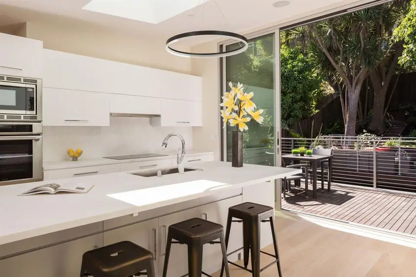 Small white modern kitchen with island and view to patio