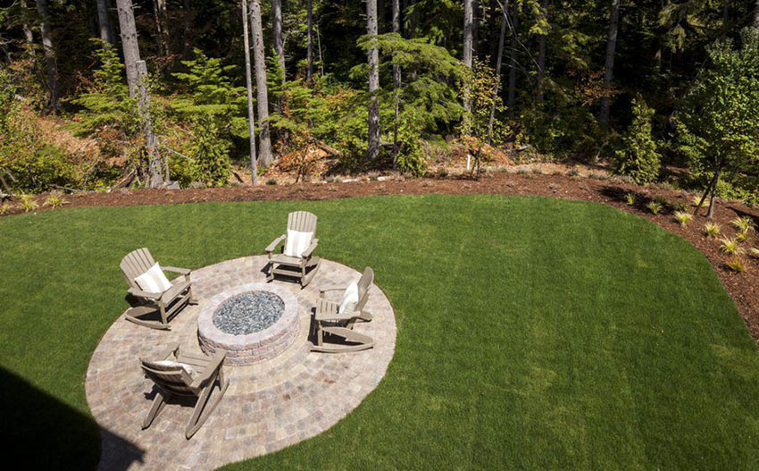 Stone patio with round fire pit with grass border