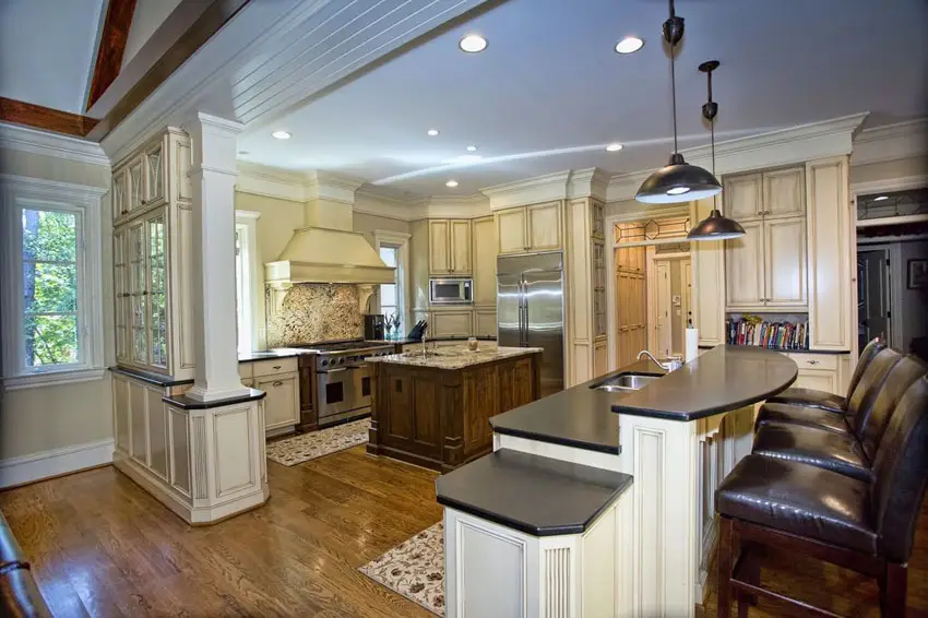 Kitchen with tri-level bar with mosaic backsplash and industrial type ceiling lights