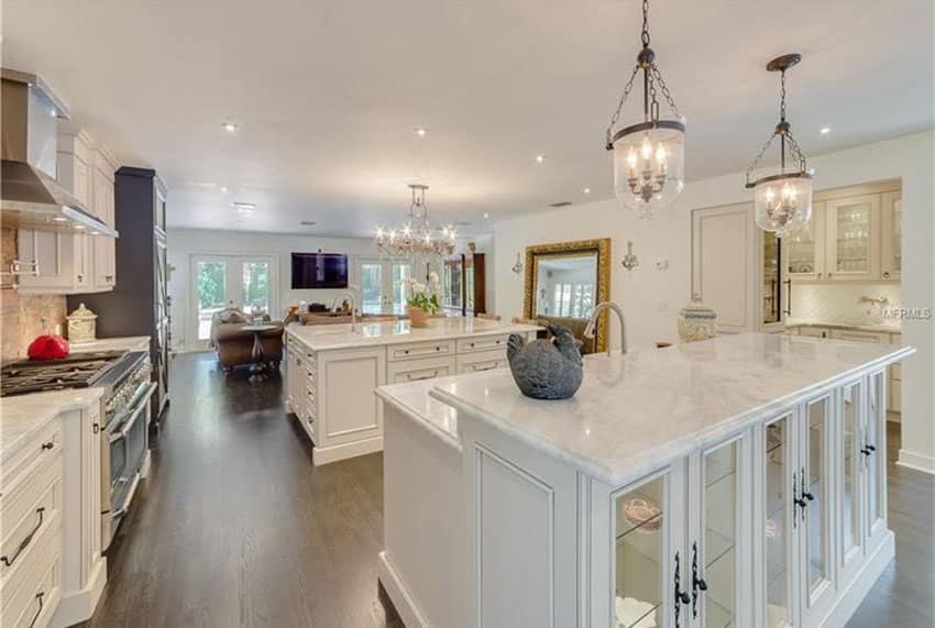 Traditional kitchen with dual islands with calacatta carrara marble countertops, chandelier and white oak flooring