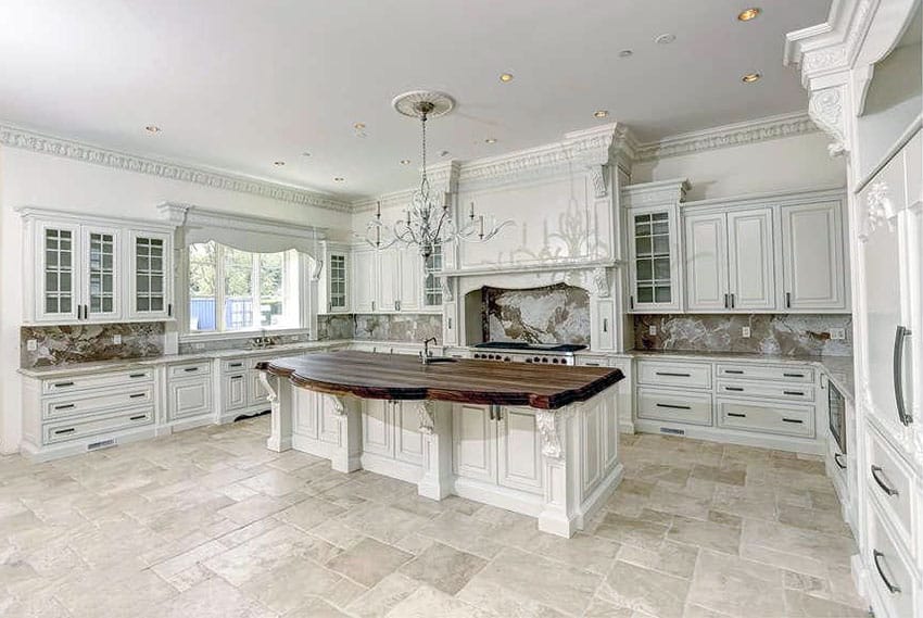 Traditional kitchen with white cabinets, honed travertine floors and wood counter island with large chandelier