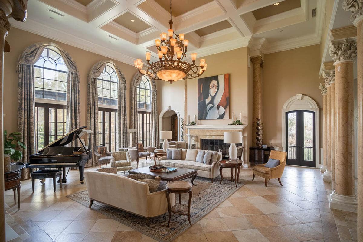 Room with arched windows, decorative fireplace, columns with moldings and chandelier