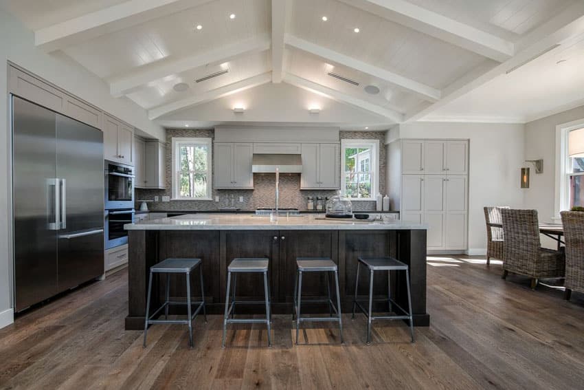 Transitional kitchen with cathedral ceiling, large rectangular island and wide plank wood floors