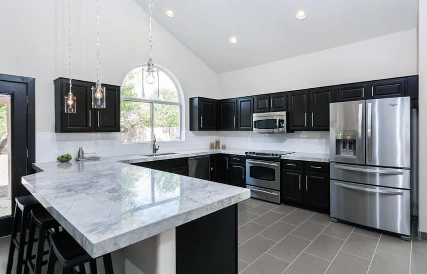 Transitional kitchen with dark cabinets, dining peninsula and calacatta carrara marble counter