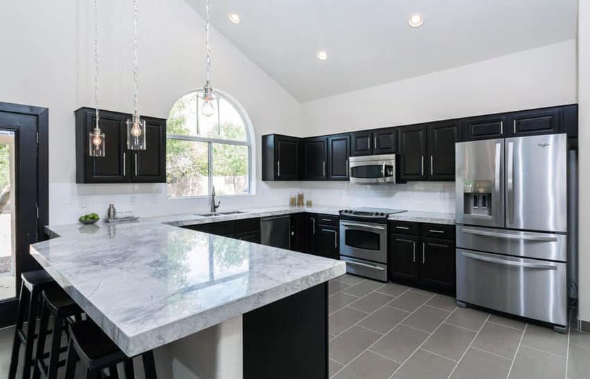 Transitional kitchen with dark-hued cabinets, dining peninsula and calacatta carrara marble 