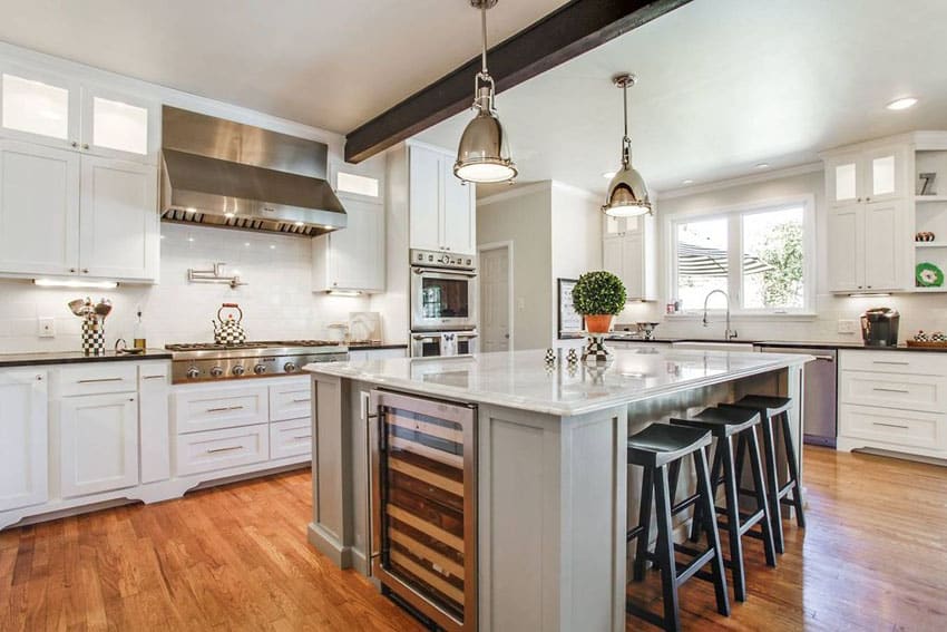 Transitional kitchen with white cabinets, gray island, thassos subway tile backsplash, nickel pendant lights and marble countertops