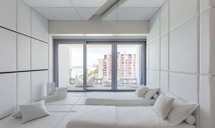 Japanese inspired white bedroom with tufted walls and balcony view of ocean