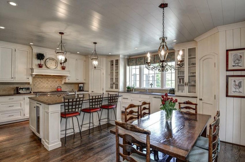 White country kitchen with recessed panel cabinets, black granite counters, dining island and dark hardwood floors