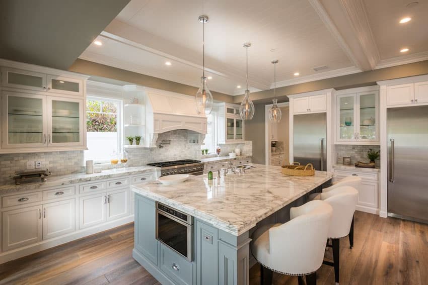 White kitchen with calacatta carrara marble counter and moody blue color island with bar stool seating