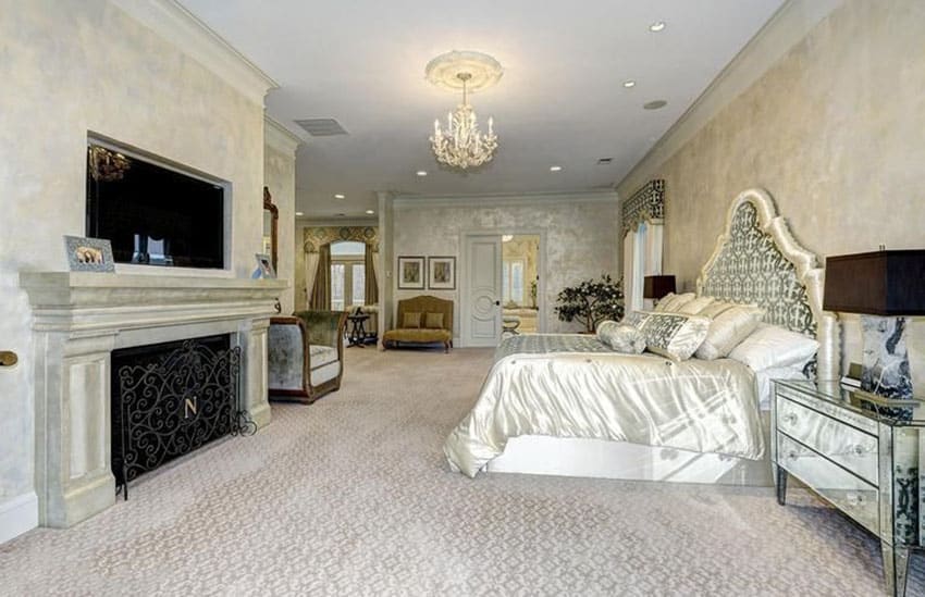 Beautiful bedroom with custom bed, mirrored furniture, chandelier, fireplace and fire screen