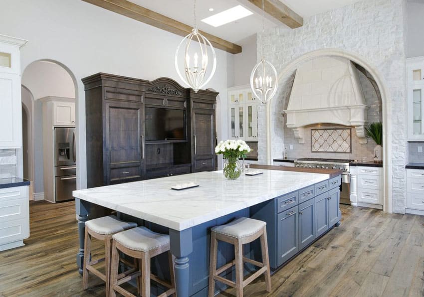 Kitchen with white cabinets and large dark blue island and bianco venatino marble countertops