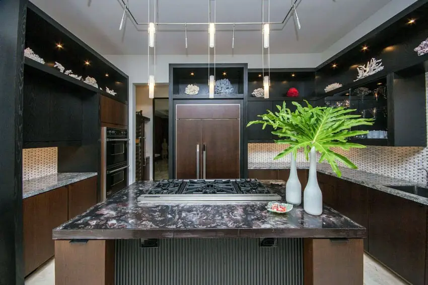 Brown island and light color backsplash in a predominantly black kitchen