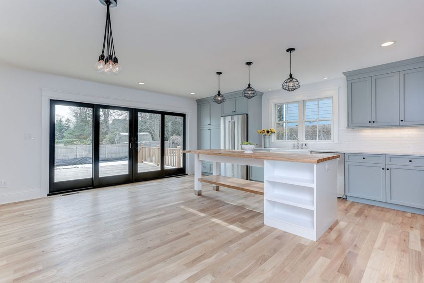 Blue cabinet, white backsplash and island with wood counter 