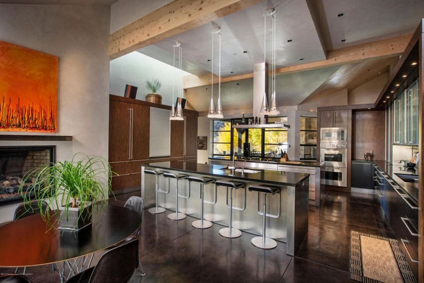 Modern rustic kitchen with concrete floors, exposed beams, black counters and piston chrome bar stools