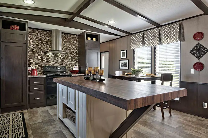 Kitchen with wood wainscoting, white base island and dark wooden cabinets