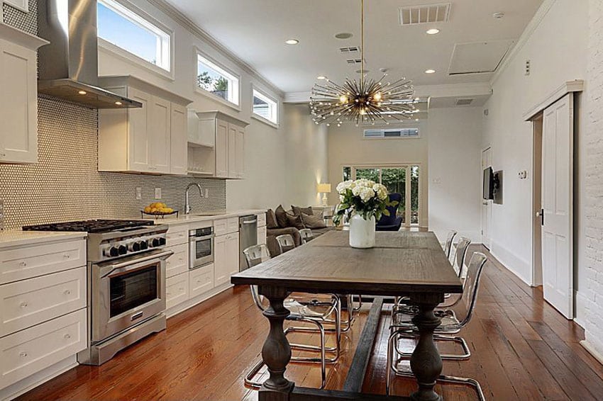 Contemporary one wall kitchen with white cabinets, wood floors and wood dining table