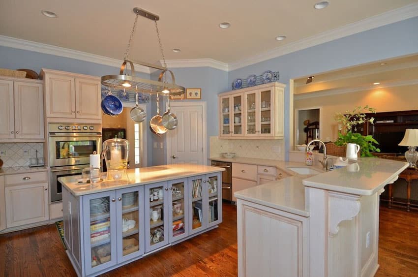 Country kitchen with blue island with glass door storage, red oak wood flooring and two level breakfast bar