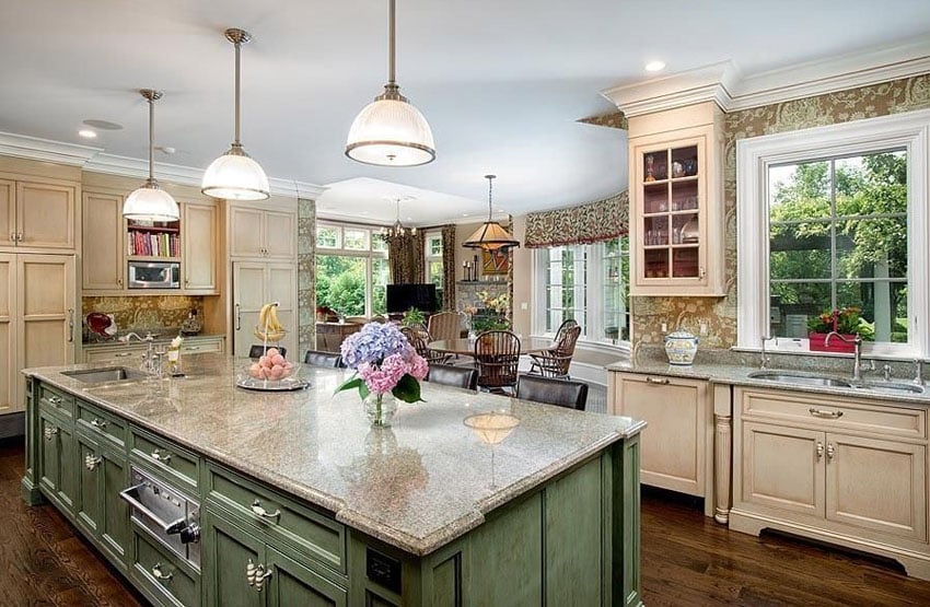 Country kitchen with green island cream color cabinets wood floors and patterned wallpaper