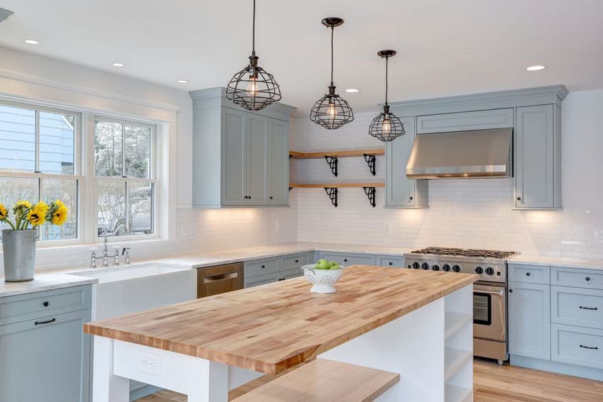 Farmhouse kitchen with light blue cabinets, single basin farmhouse sink, viking range and wood counter island painted white