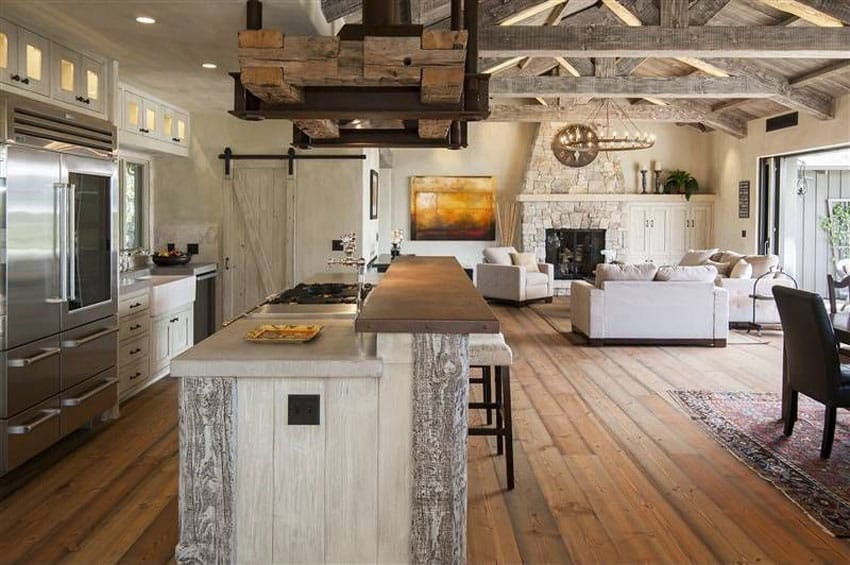 Country kitchen with single basin farmhouse sink, sliding barn door and reclaimed barn wood island with two level breakfast bar