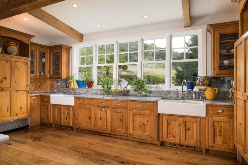 Country kitchen with two farmhouse sinks, glass door cabinetry, wood beam ceiling and wood floors